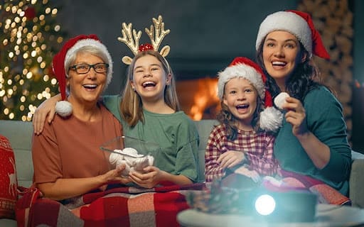 Senior lady with grandchildren watching movie by christmas tree