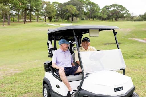 two senior men on golf cart smiling